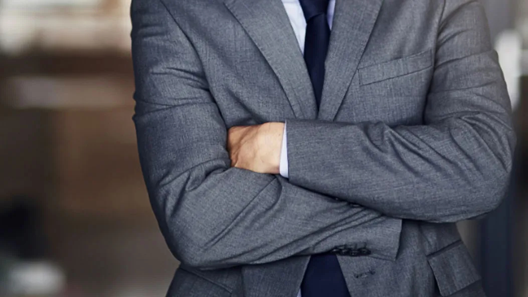 Hombre de traje cruzado de brazos, como si tuviera frío
