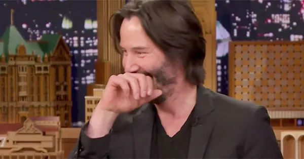 Keanu Reeves cubriéndose parcialmente la cara con la mano