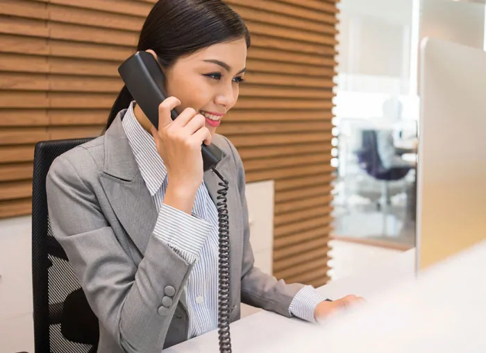 Recepcionista sonriendo mientras atiende el teléfono